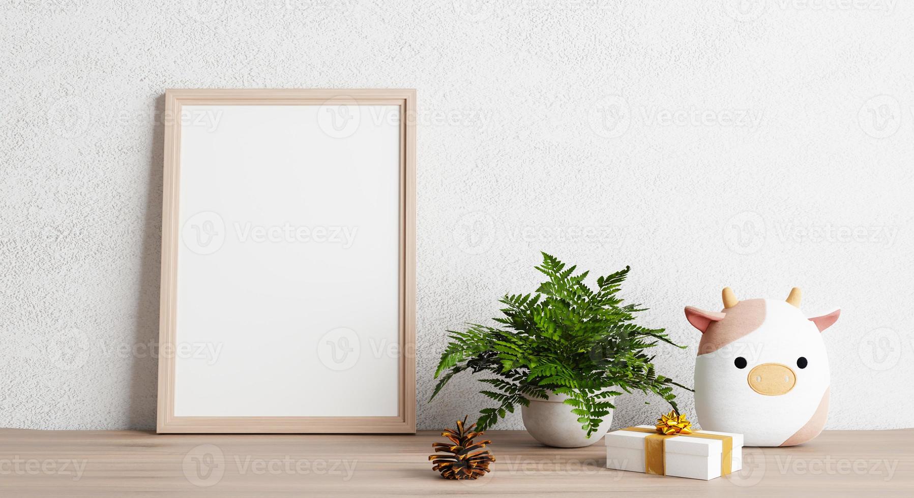 Empty photo frame mockup on wooden table with cow doll plant pine cone and gift box. Art and decoration concept. 3D illustration rendering