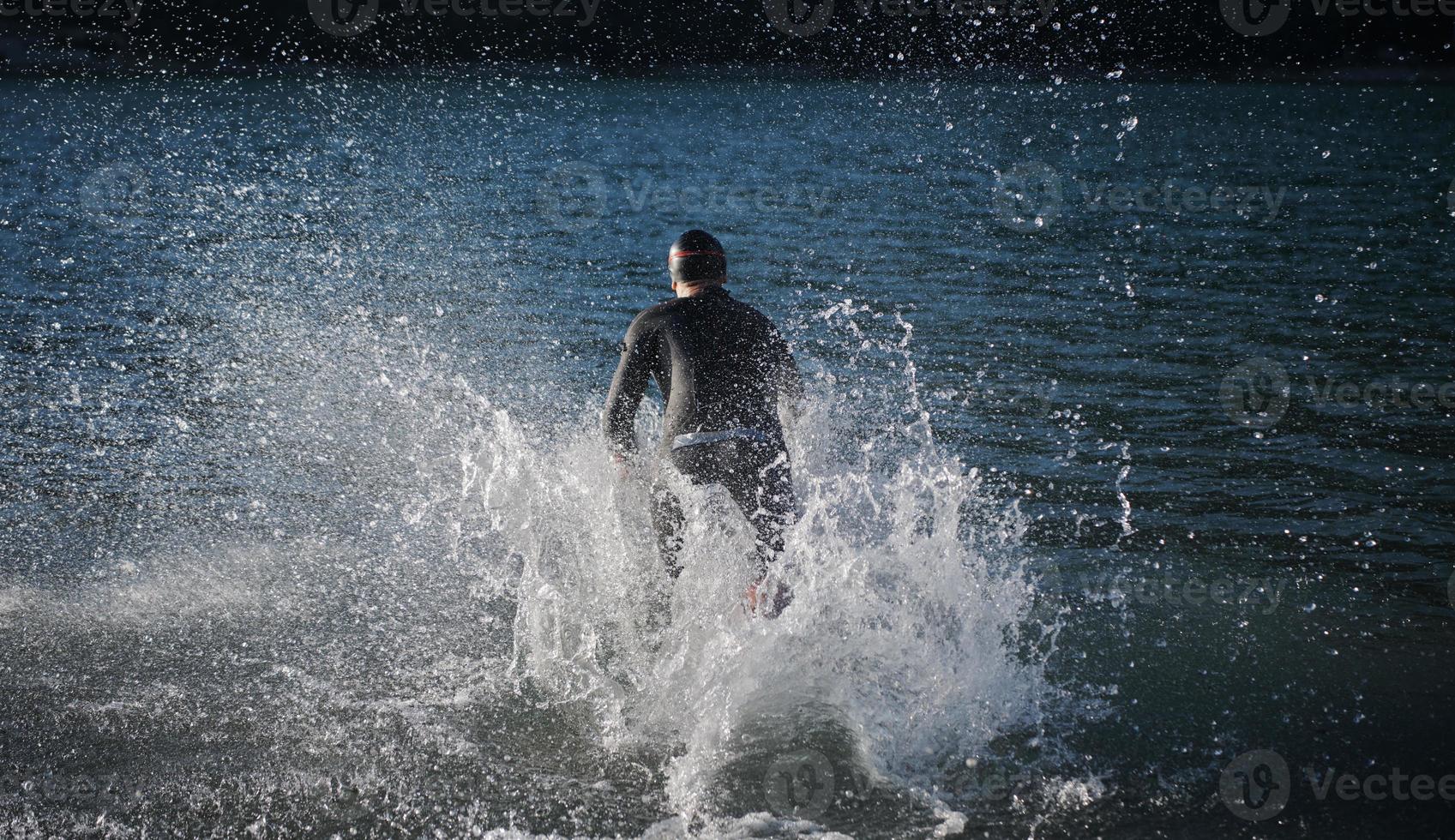 triathlon athlete starting swimming training on lake photo