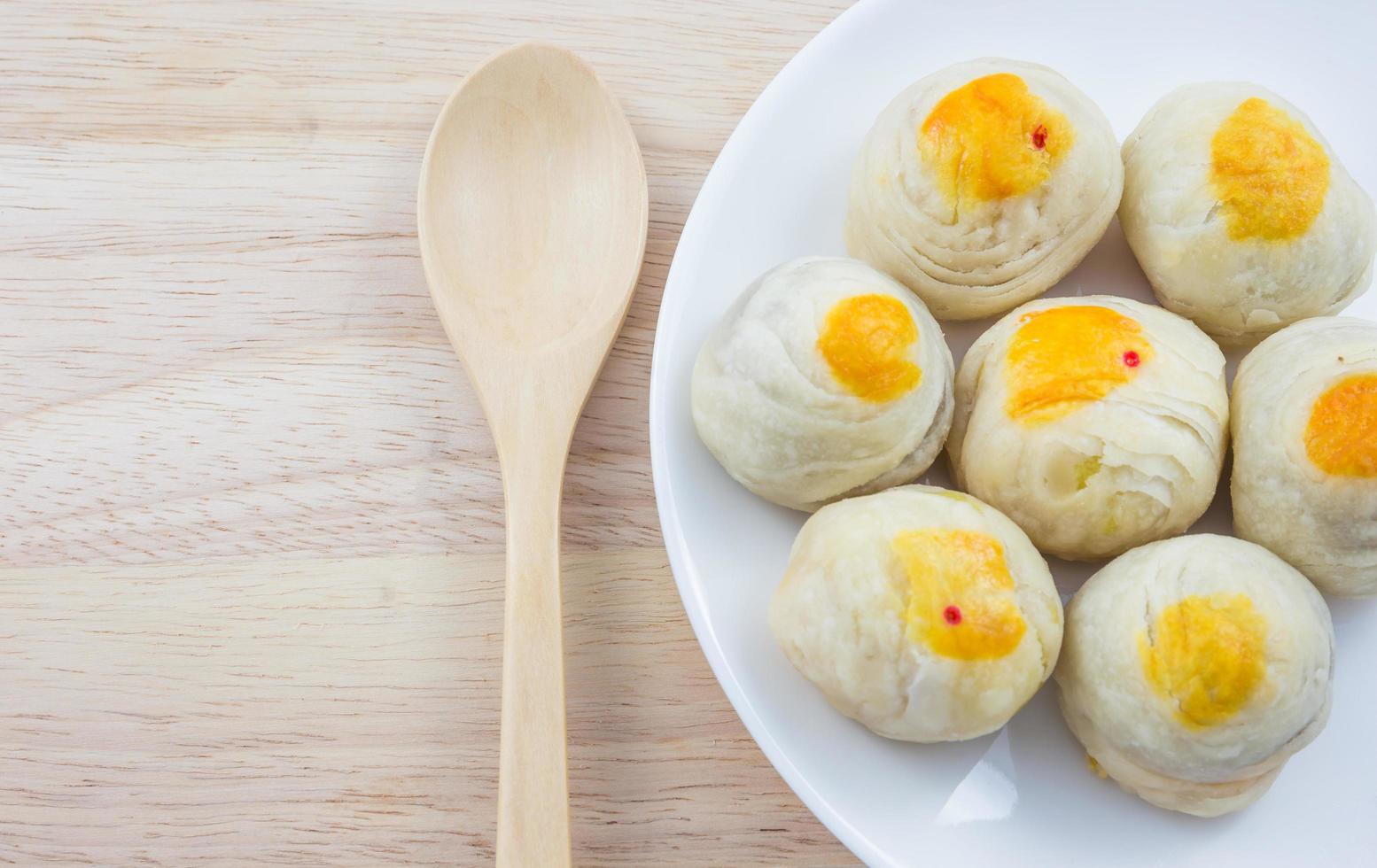 Chinese Pastry Mung Bean or Mooncake with Egg Yolk on dish and wooden table spoon photo