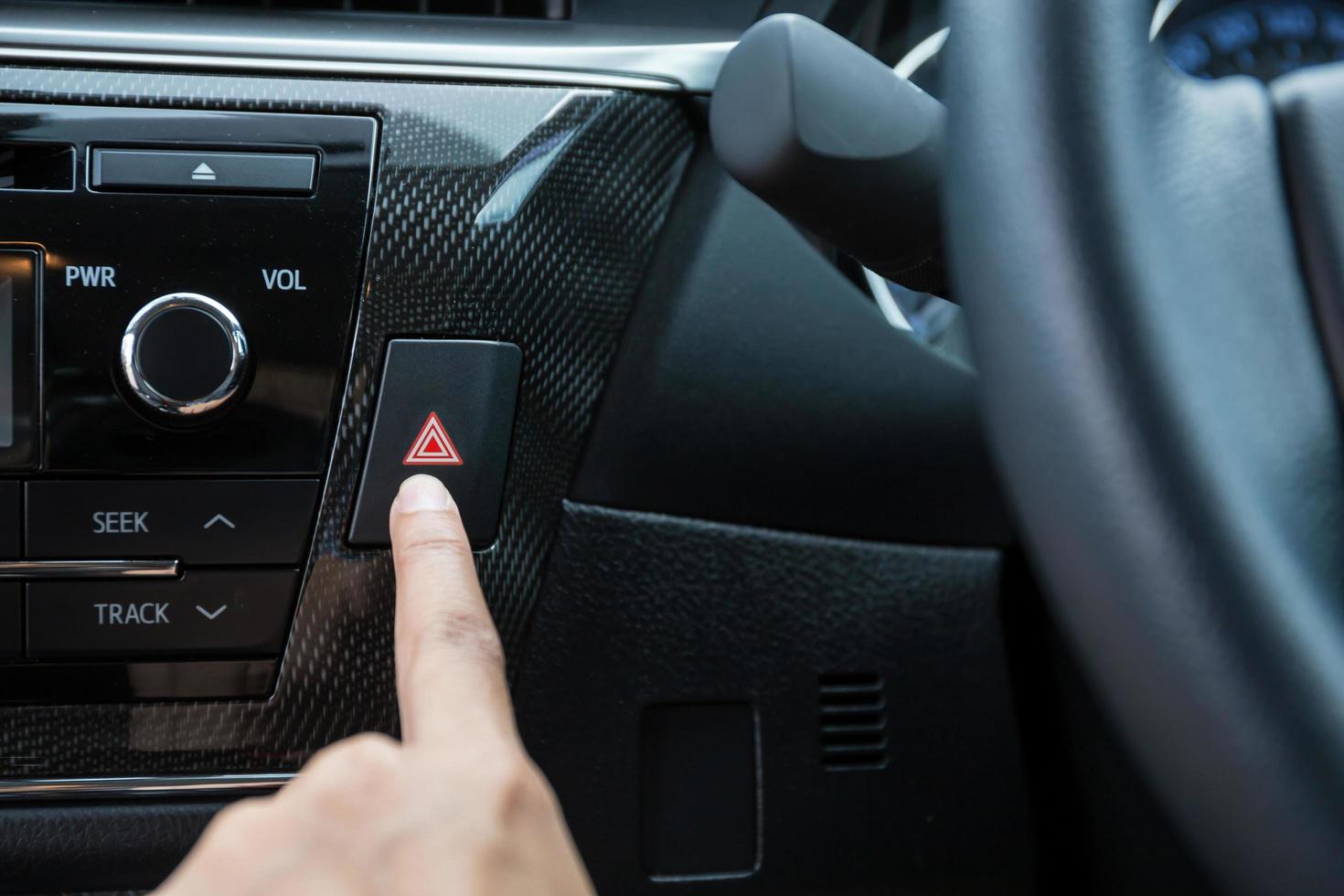 Closeup of young woman pressing emergency button on car sport dashboard. photo