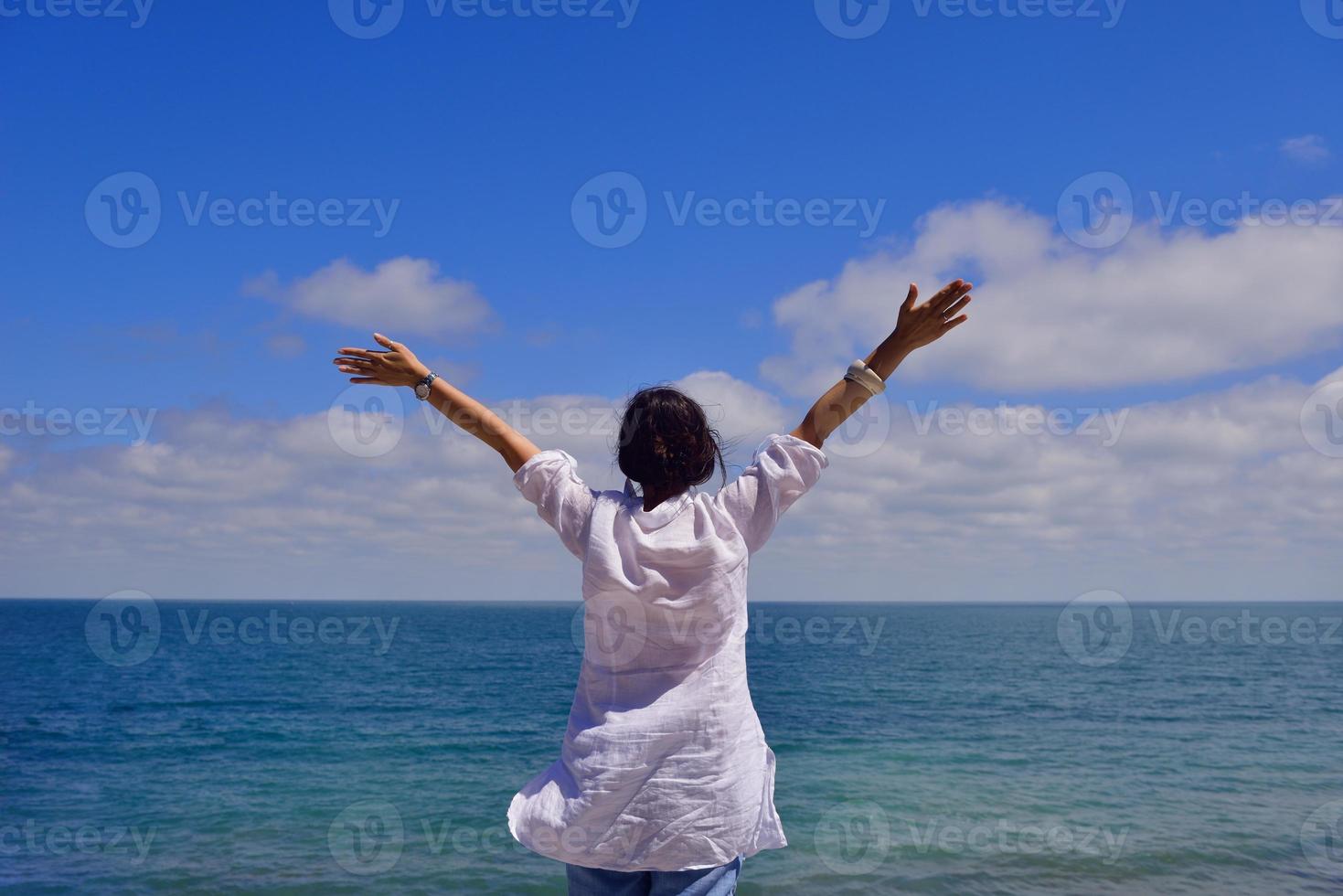 young woman with spreading arms to sky photo