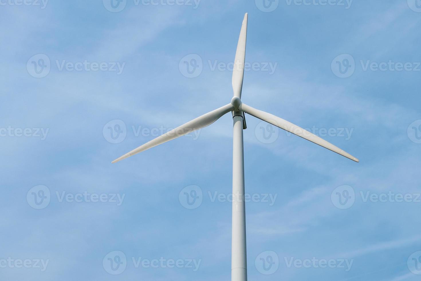 rotating blades of a windmill propeller on blue sky background. Wind power generation. Pure green energy. photo