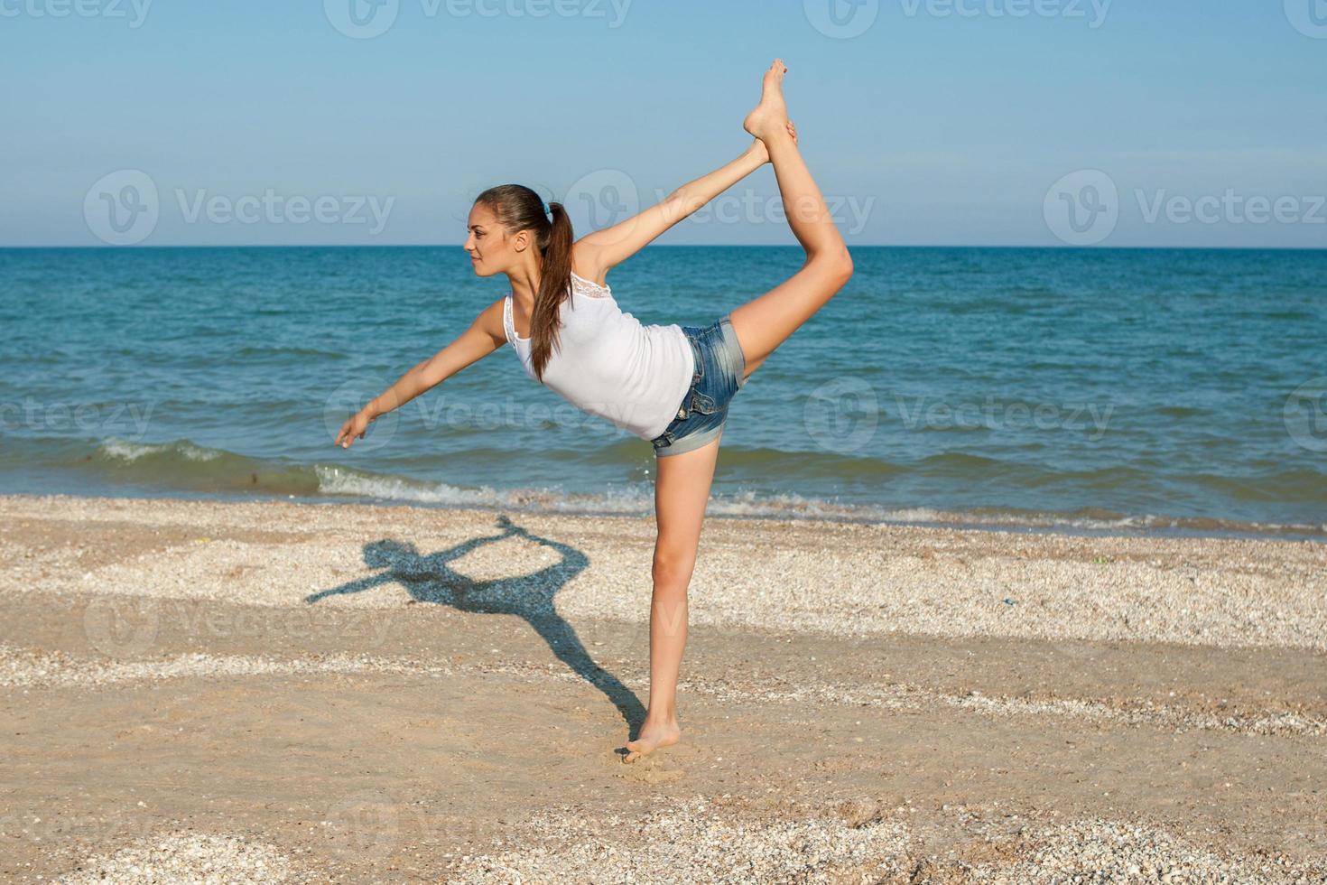 mujer joven practicando yoga o fitness en la orilla del mar foto