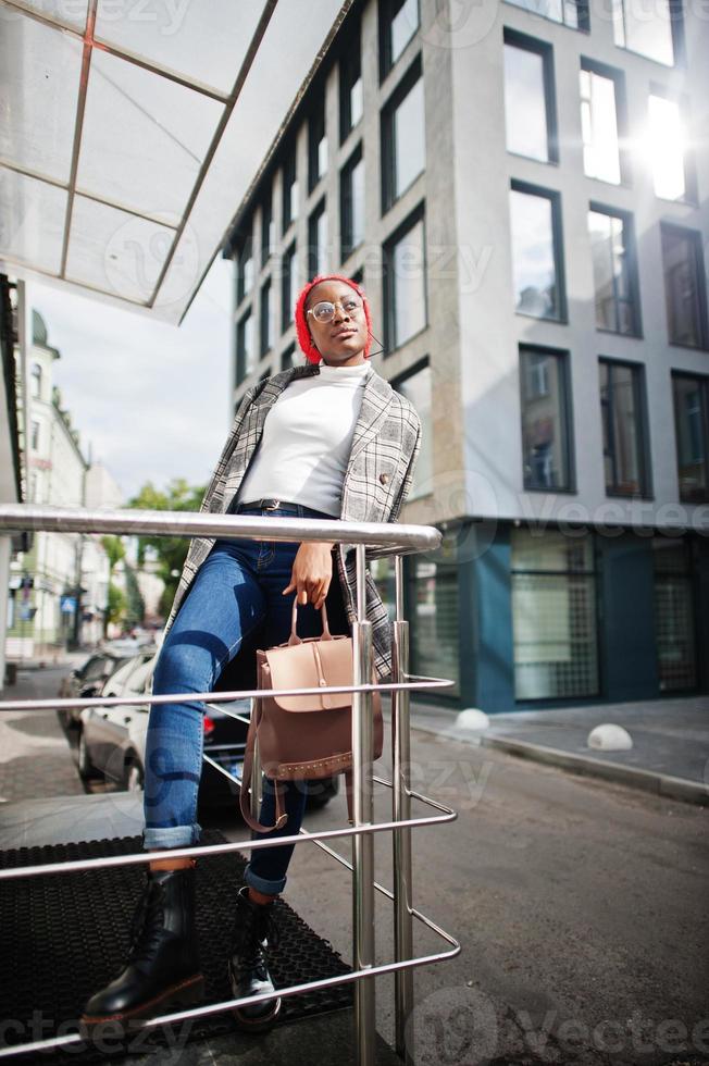 Young modern fashionable, attractive, tall and slim african muslim woman in hijab or turban head scarf speak on mobile phone against city. photo