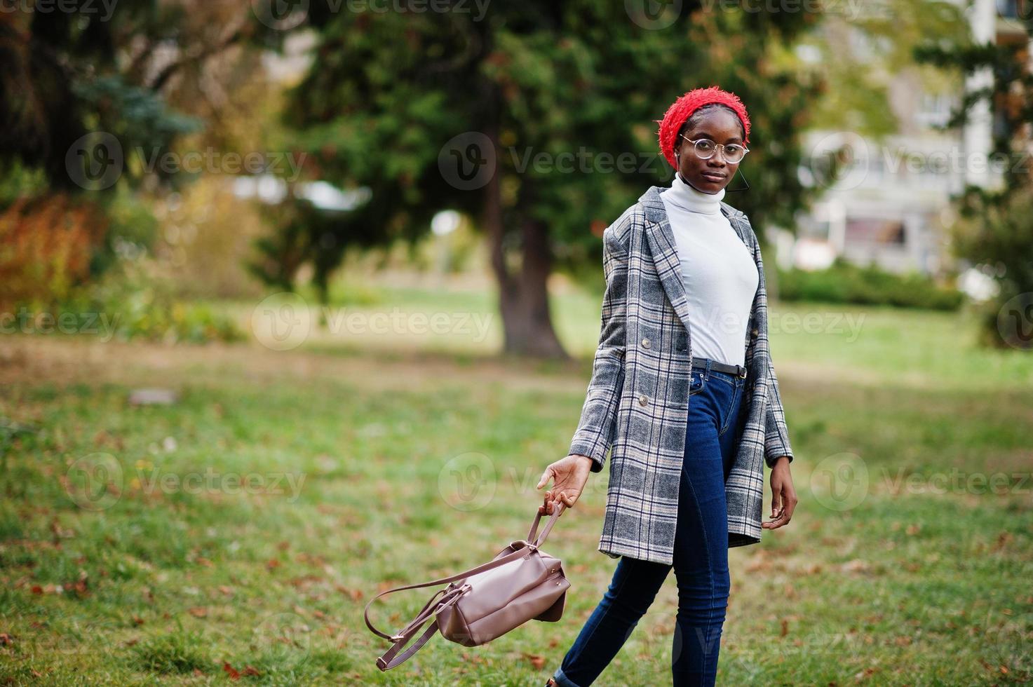Young modern fashionable, attractive, tall and slim african muslim woman in hijab or turban head scarf and coat posed at park. photo