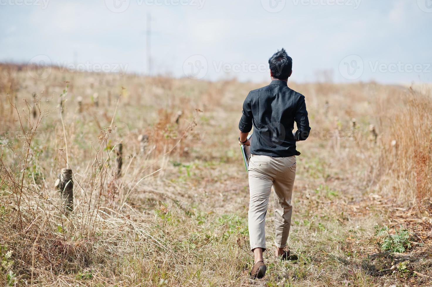 South asian agronomist farmer with clipboard inspecting cut trees in the farm garden. Agriculture production concept. photo
