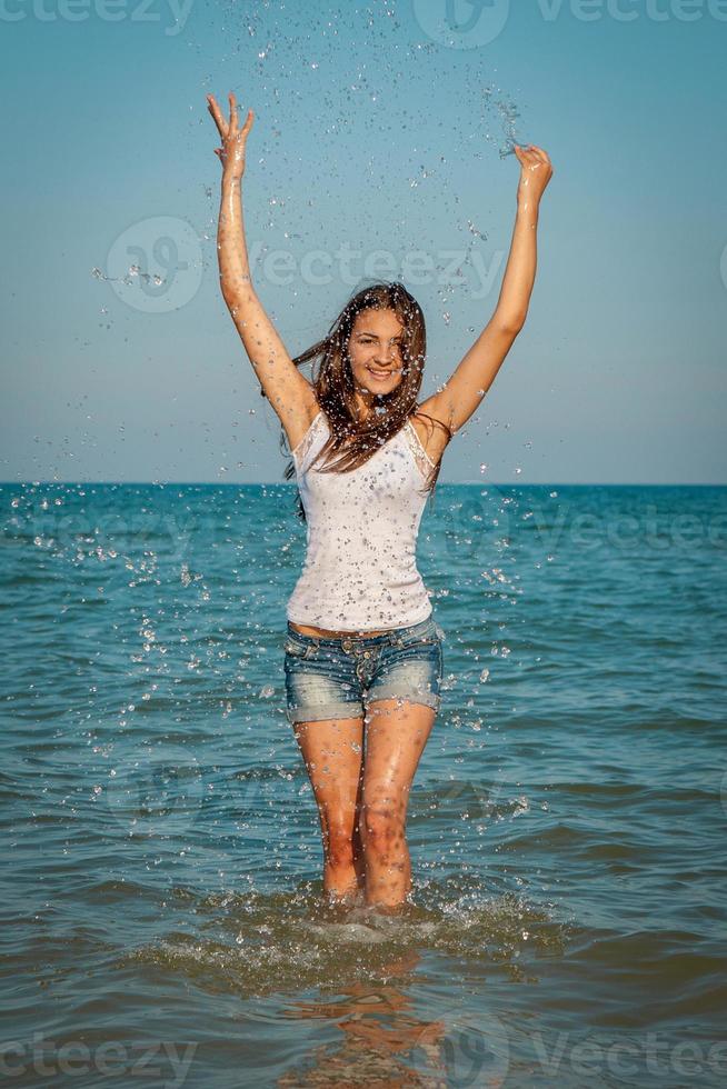 young girl splashing the water in the sea photo