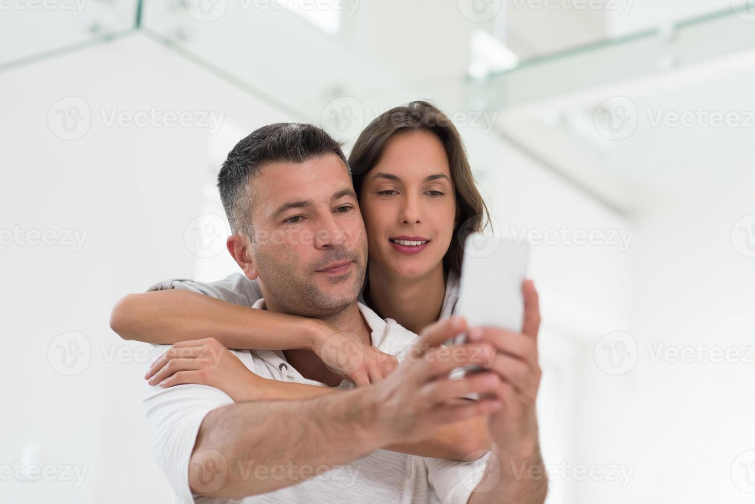 happy couple using mobile phone at home photo