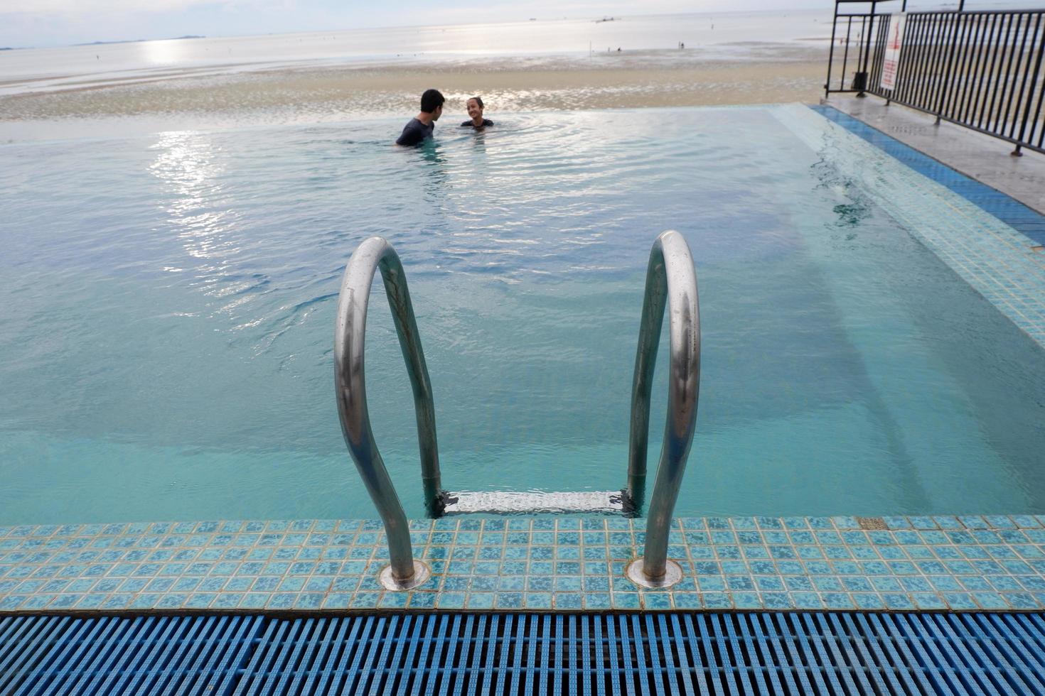 Papua, Indonesia - October 10, 2021. People swimming in the pool near the sea photo