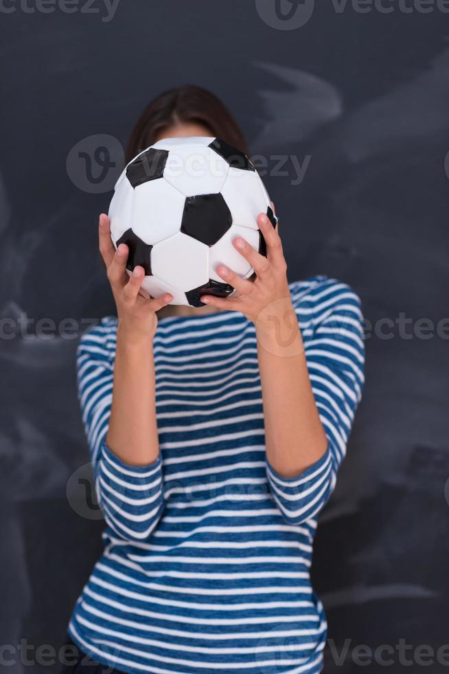 woman holding a soccer ball in front of chalk drawing board photo