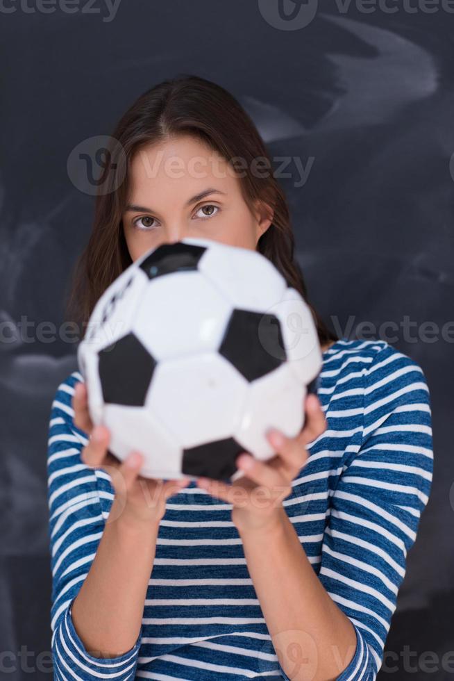 woman holding a soccer ball in front of chalk drawing board photo