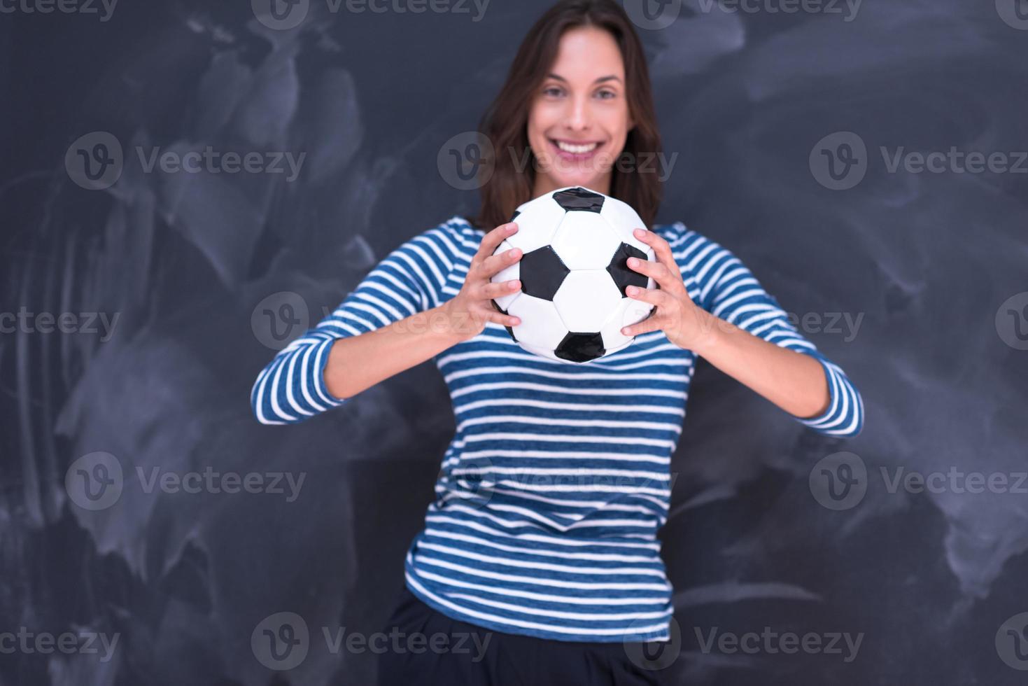 mujer sosteniendo una pelota de fútbol frente a un tablero de dibujo de tiza foto