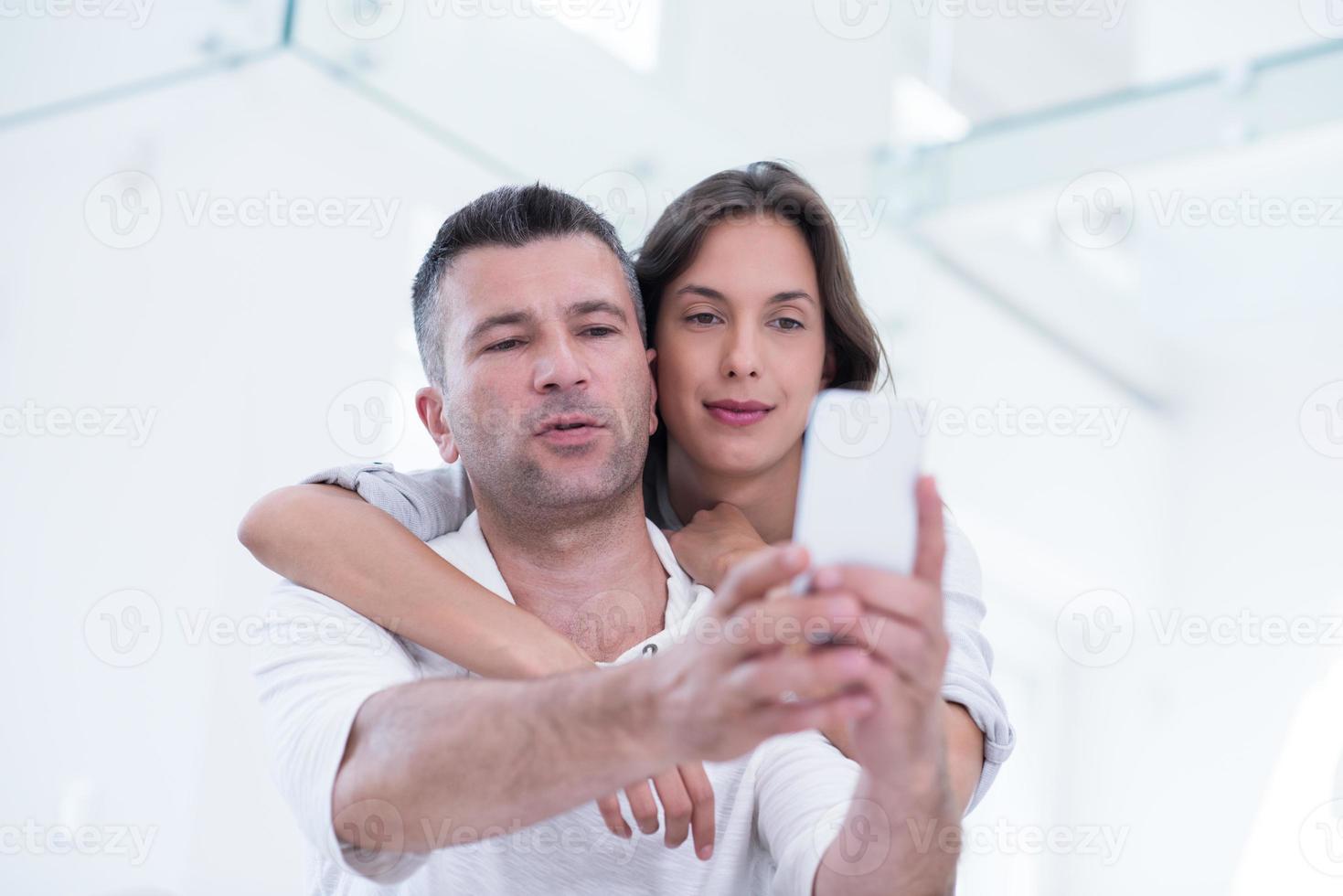 happy couple using mobile phone at home photo