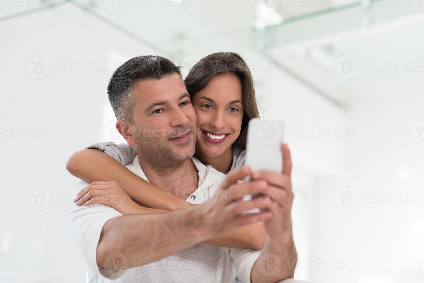 happy couple using mobile phone at home photo