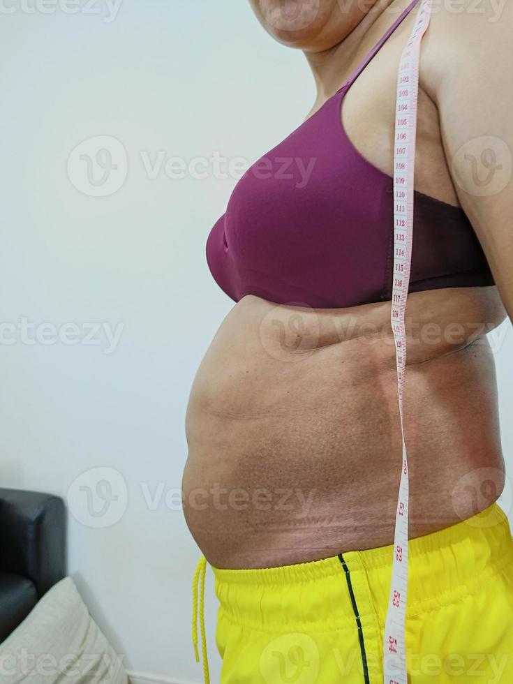 Side view. Shabby fat Asian woman standing showing her belly photo