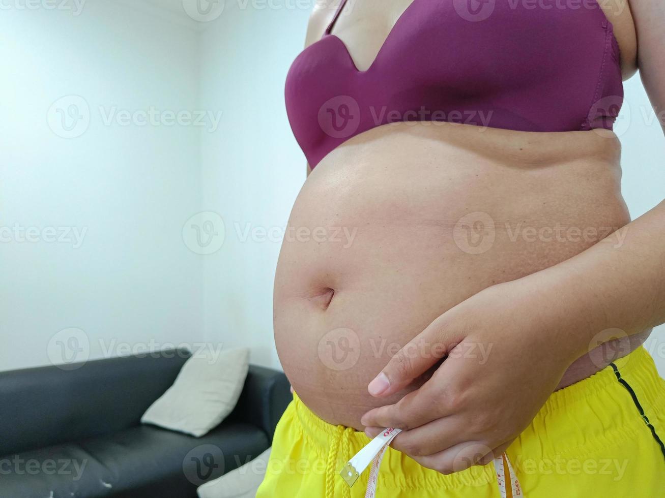 front view. Shabby fat Asian woman standing showing her belly photo