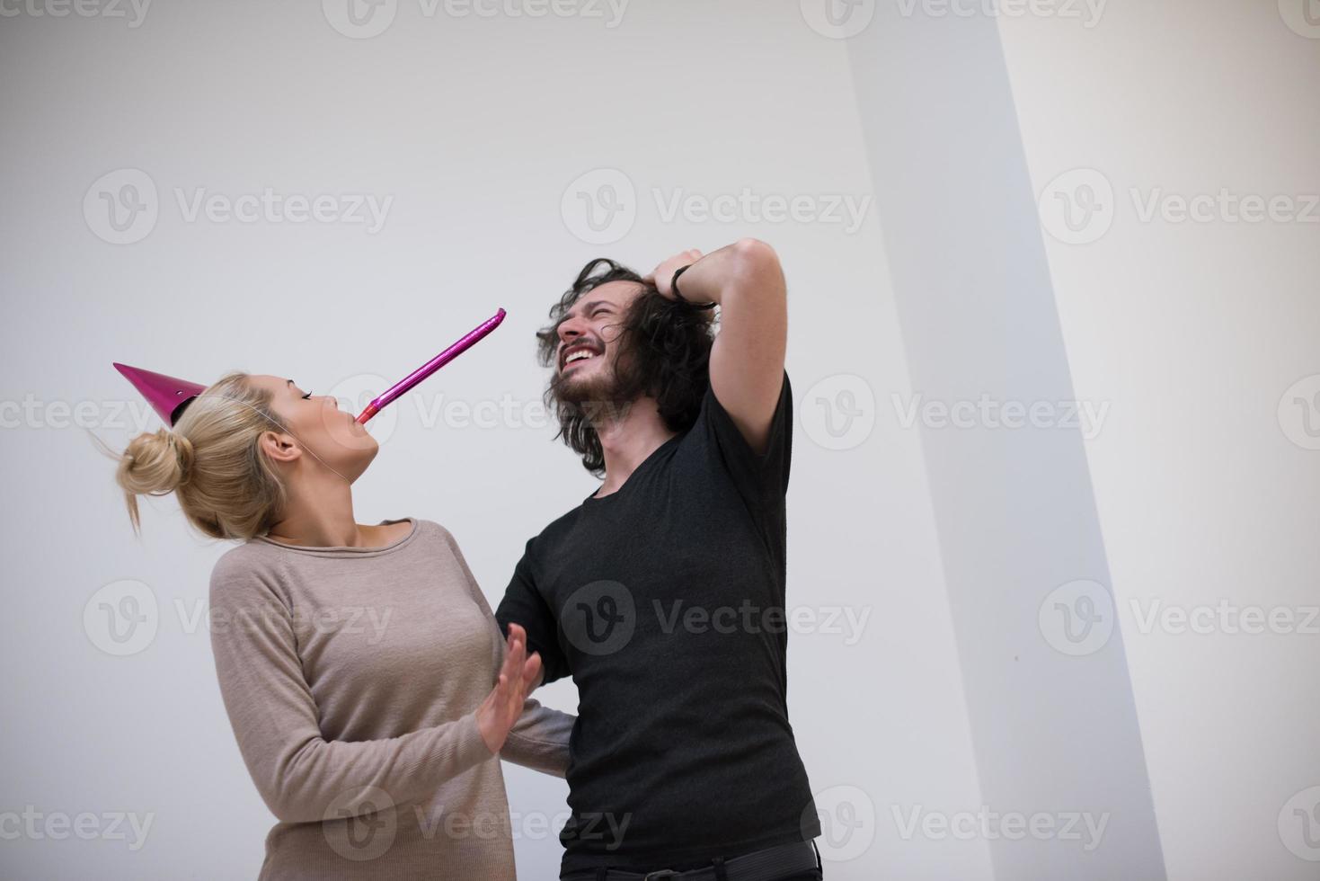 couple in party hats blowing in whistle photo