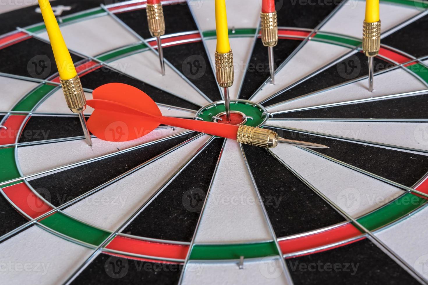 Red and yellow dart arrows hitting in the target center of dartboard. Success hitting target aim goal achievement concept photo