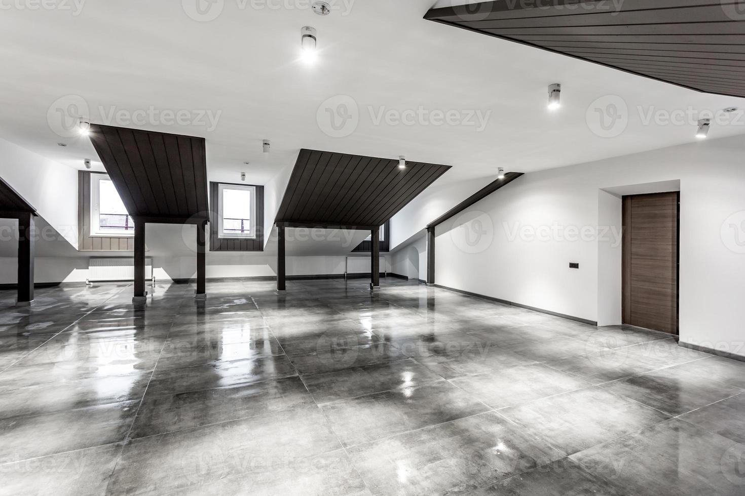 Empty unfurnished loft mansard room interior with wooden columns and wet concrete floor on roof level in black and whote style color photo