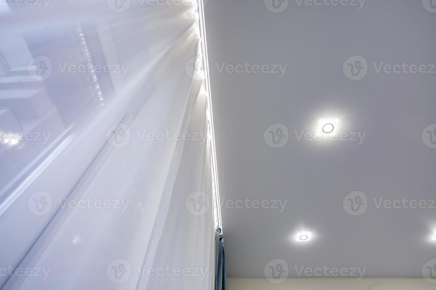 halogen spots lamps on suspended ceiling and drywall construction in in empty room in apartment or house. Stretch ceiling white and complex shape. photo