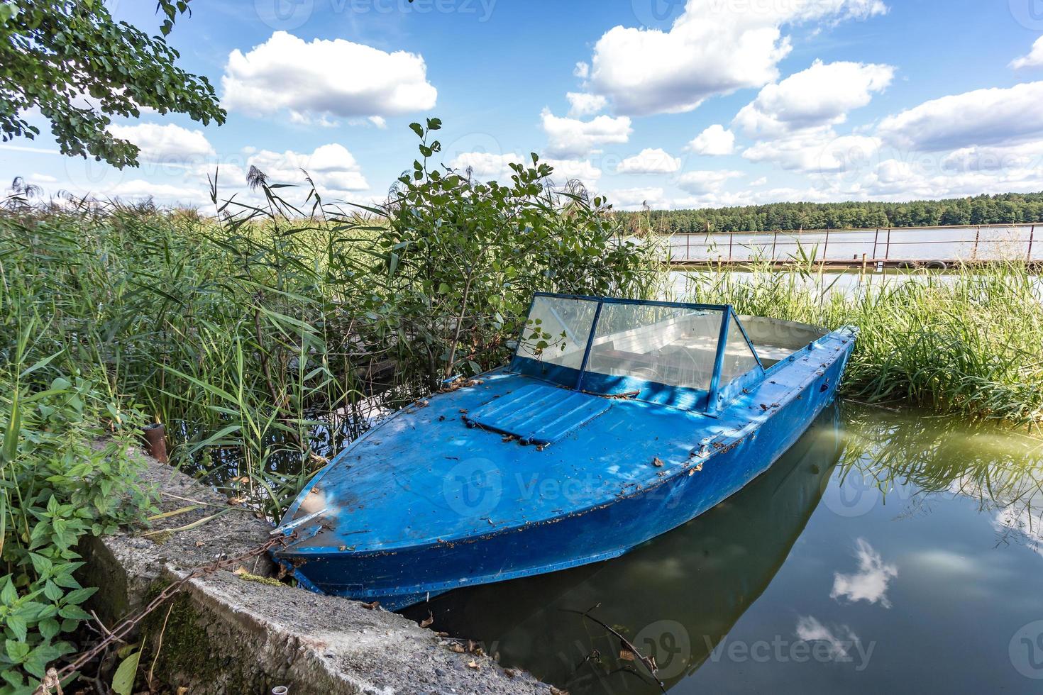 old wooden blue boat on the bank of a wide river in sunny day photo
