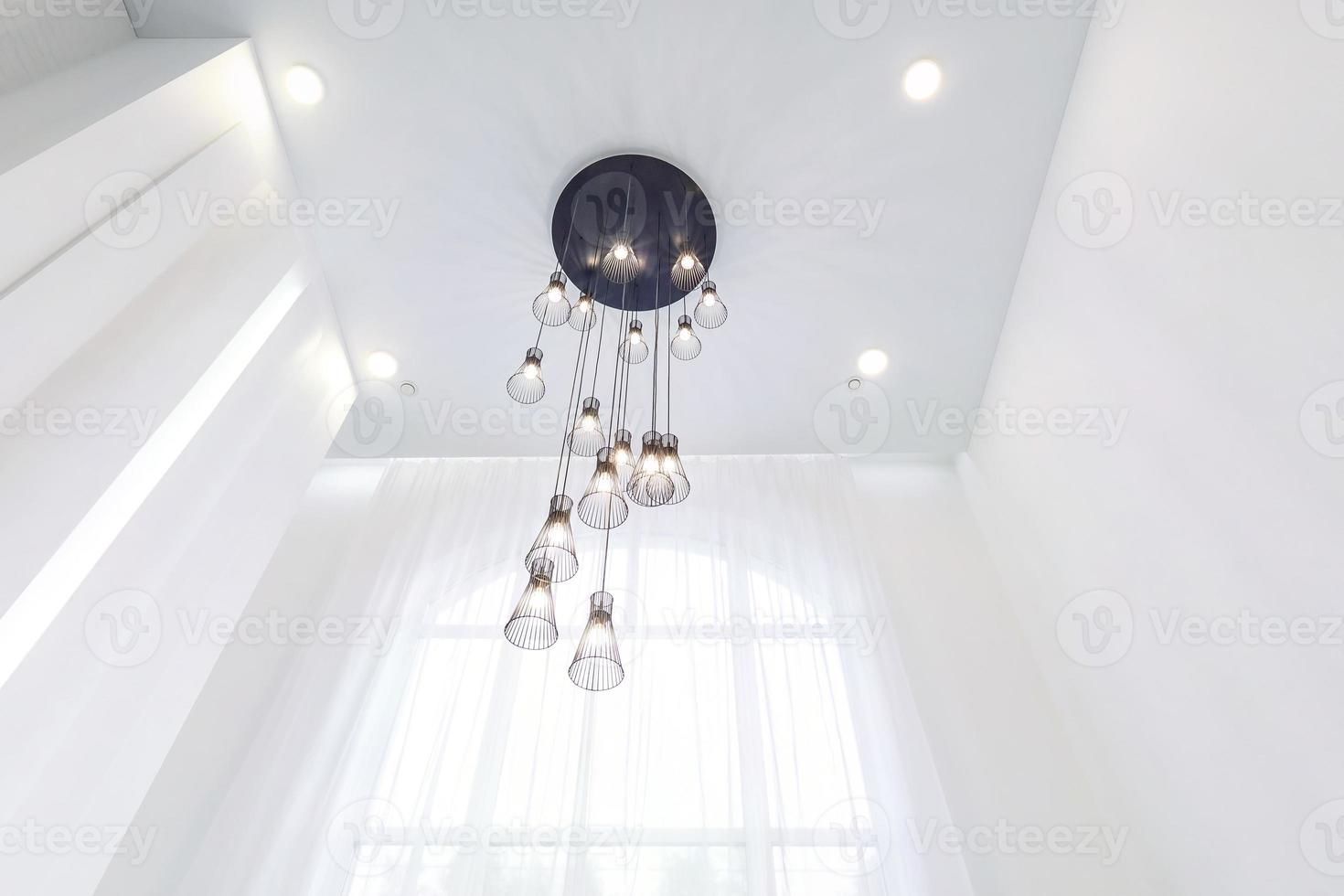 looking up on suspended ceiling with halogen spots lamps and drywall construction in empty room in apartment or house. Stretch ceiling white and complex shape. photo