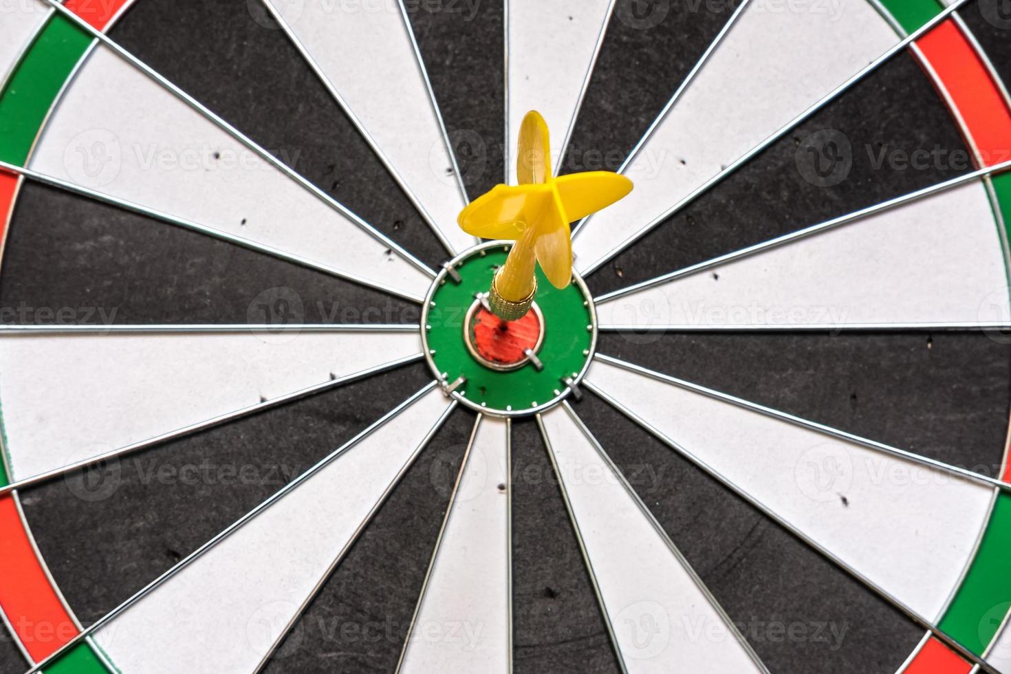 Red and yellow dart arrows hitting in the target center of dartboard. Success hitting target aim goal achievement concept photo