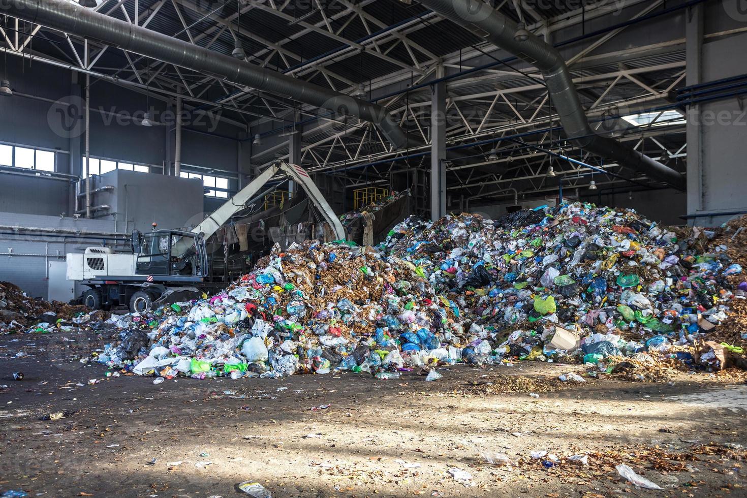 la excavadora apila basura en una gran pila en la clasificación de la moderna planta de procesamiento de reciclaje de residuos. separación y clasificación de la recolección de basura. reciclaje y almacenamiento de residuos foto