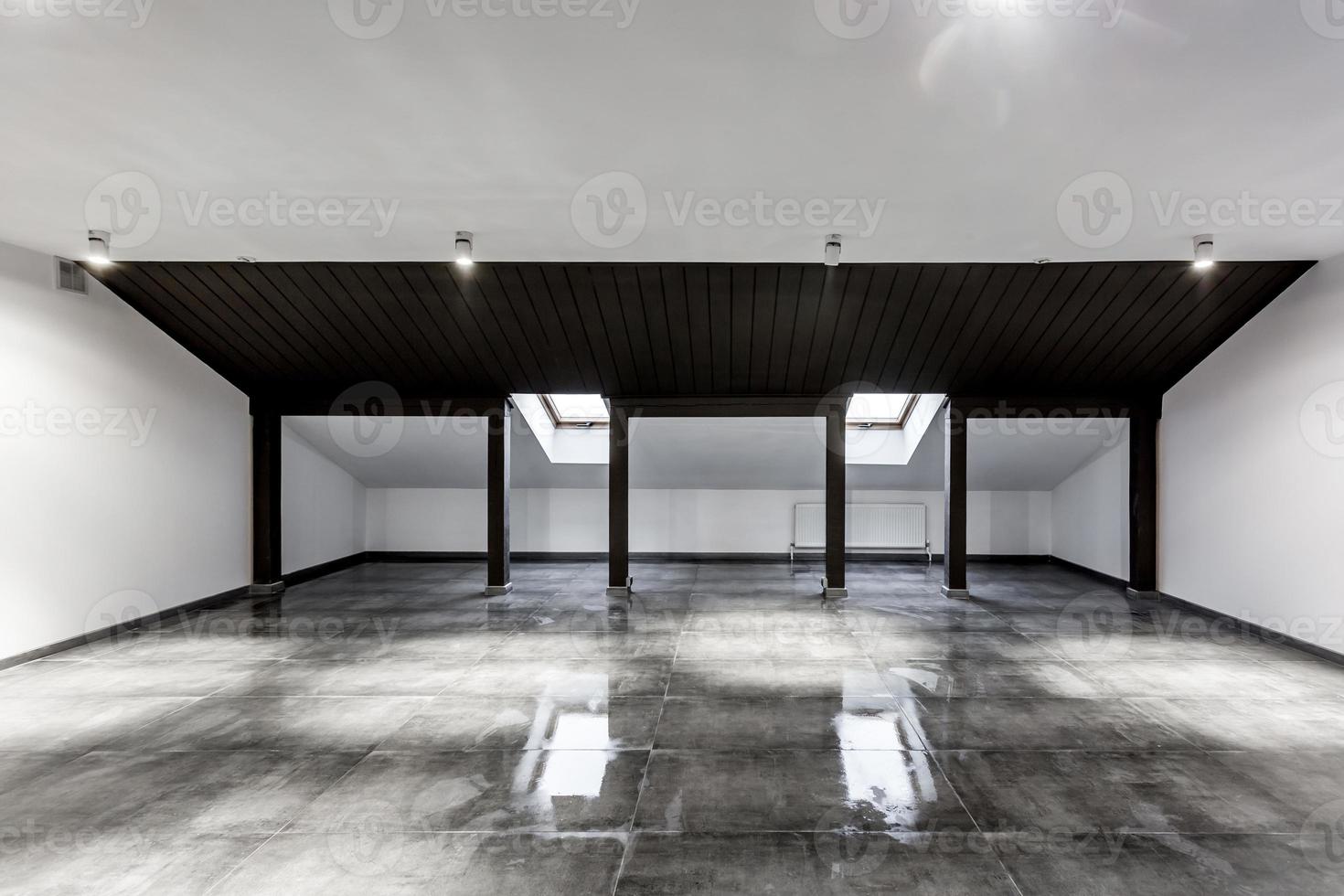Empty unfurnished loft mansard room interior with wooden columns and wet concrete floor on roof level in black and whote style color photo