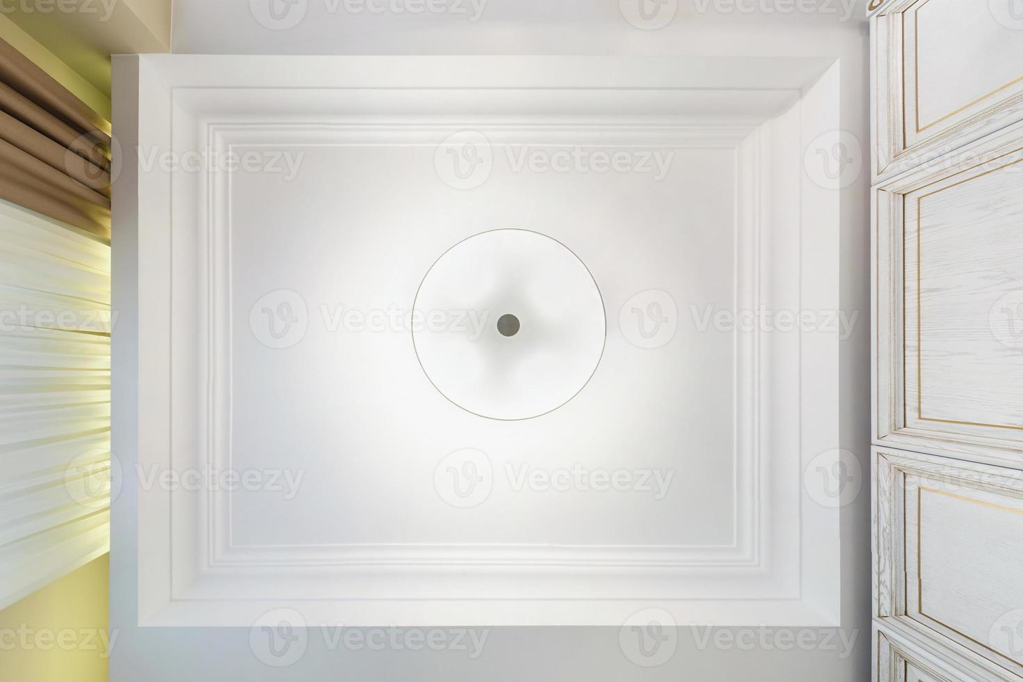 looking up on suspended ceiling with halogen spots lamps and drywall construction in empty room in apartment or house. Stretch ceiling white and complex shape. photo