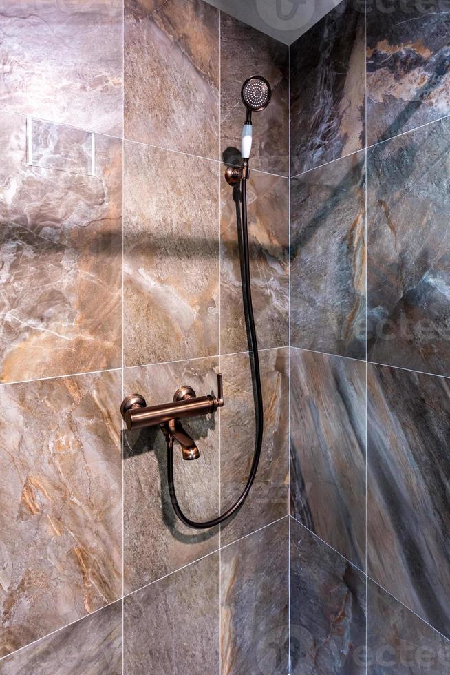 copper water tap sink with faucet in expensive loft bathroom. detail of a corner shower cabin with wall mount shower attachment photo