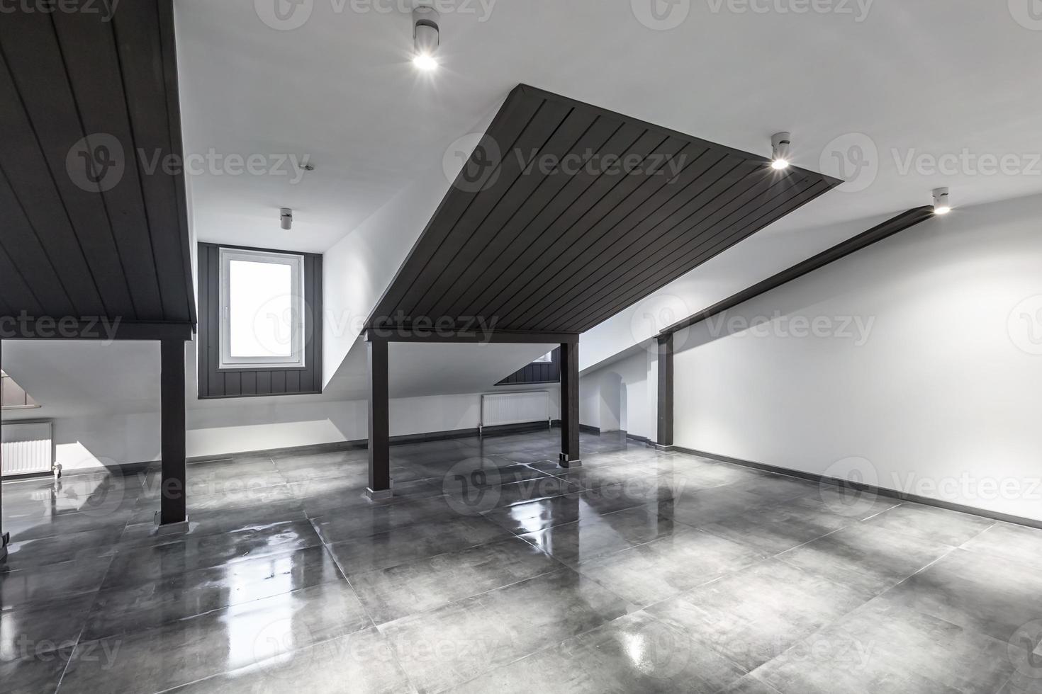 Empty unfurnished loft mansard room interior with wooden columns and wet concrete floor on roof level in black and whote style color photo