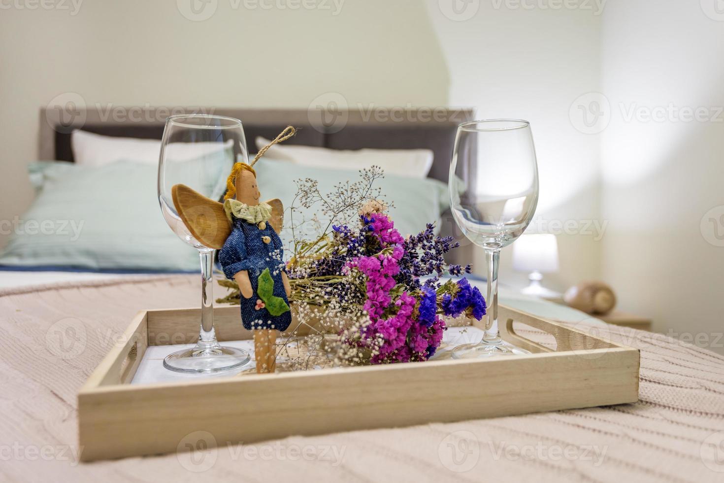 still life decoration from two empty wine glasses, a home-made rag angel toy and  bouquet of dried flowers. photo