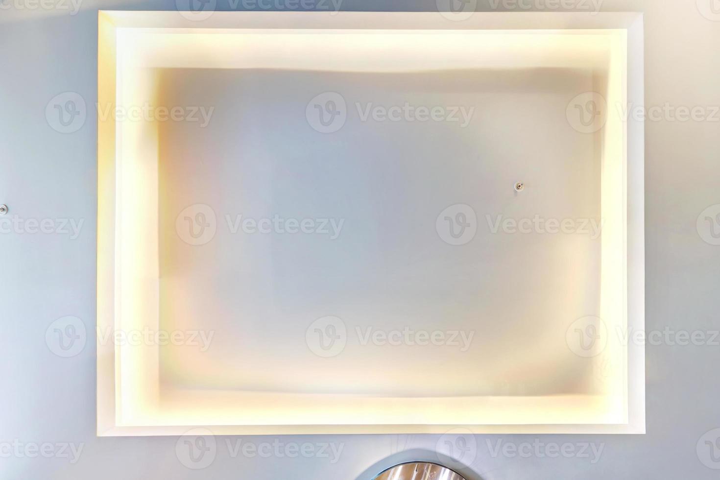 look up on suspended ceiling with halogen spots lamps and drywall construction with fire alarm sensor in empty room in apartment or house. Stretch ceiling photo