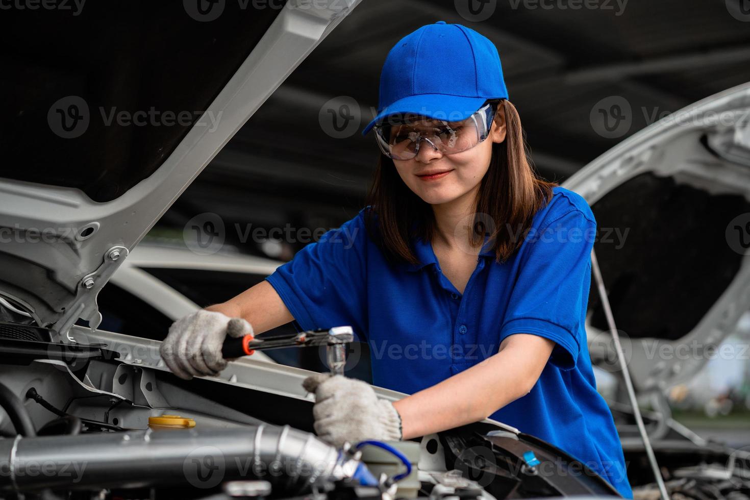 concepto de reparación de automóviles. Mecánico de automóviles de mujer asiática con camisa de acuarela en el garaje. feliz mujer mecánica en el centro de reparación de automóviles foto