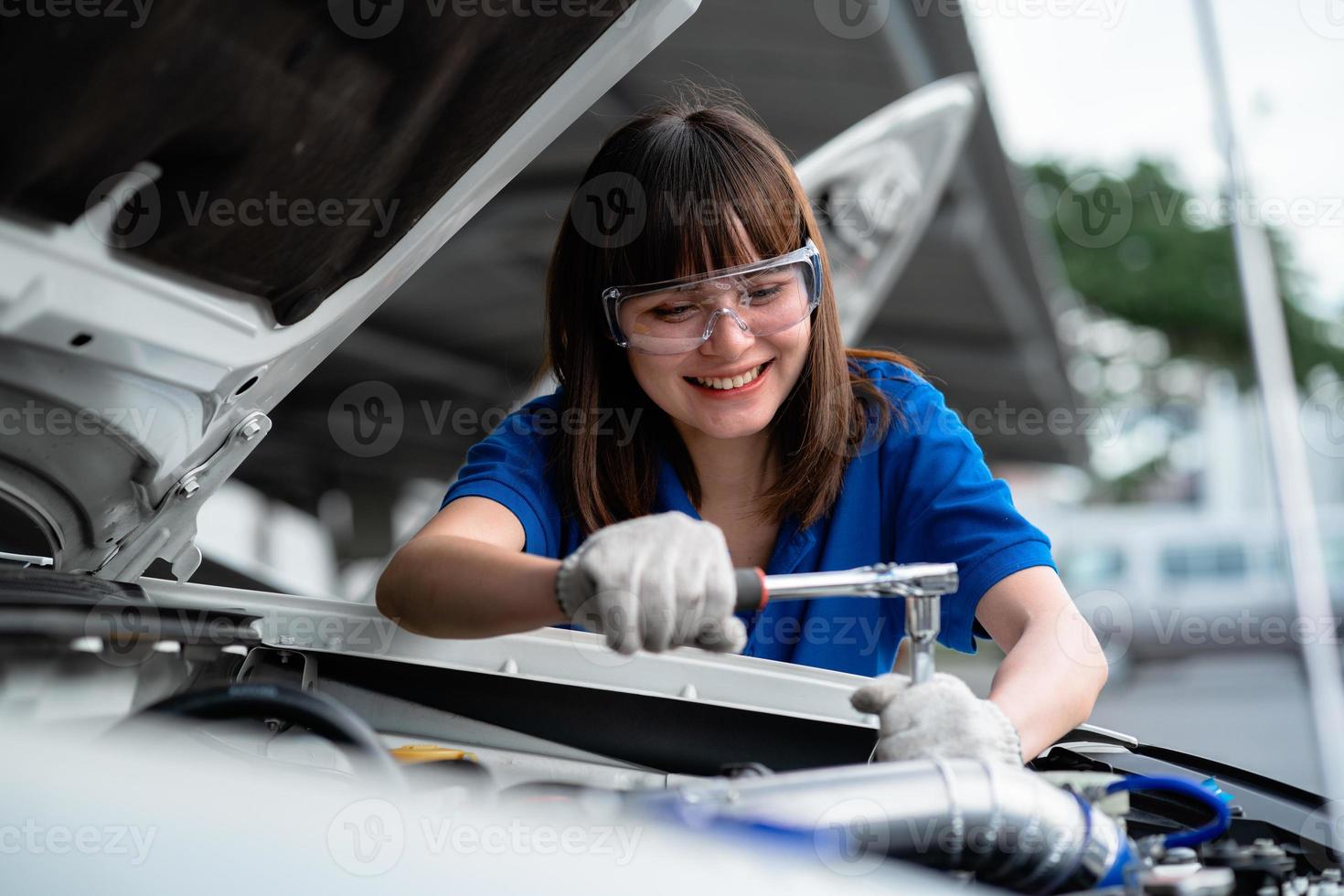 Auto repair concept. Asian woman car mechanic wearing watercolor shirt in garage. happy female mechanic in car repair cente photo