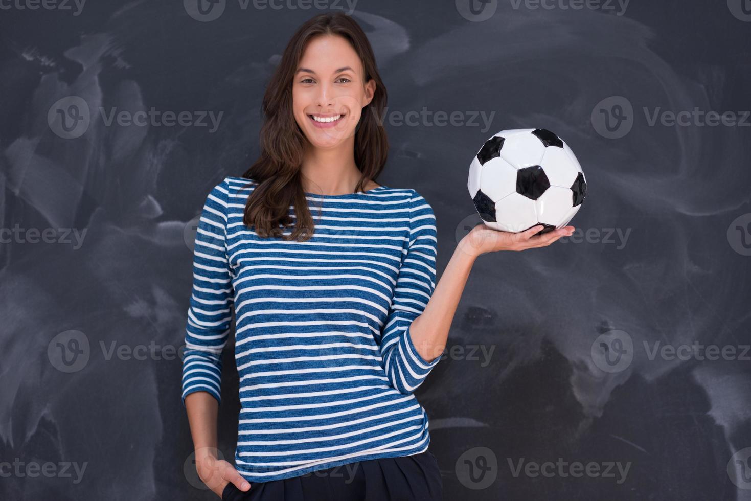 mujer sosteniendo una pelota de fútbol frente a un tablero de dibujo de tiza foto