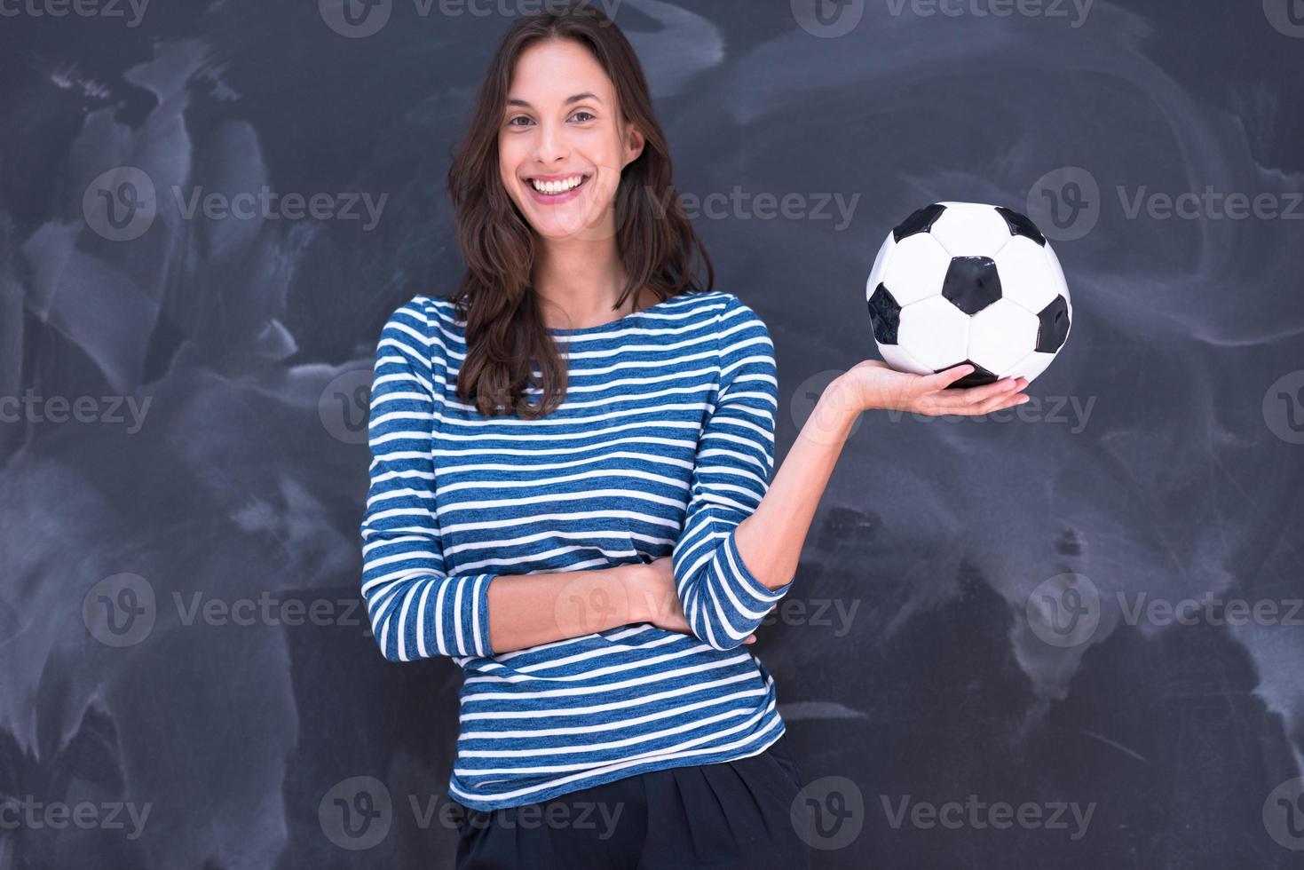 woman holding a soccer ball in front of chalk drawing board photo