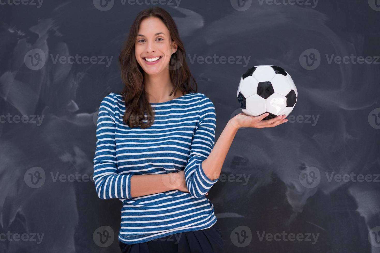 mujer sosteniendo una pelota de fútbol frente a un tablero de dibujo de tiza foto