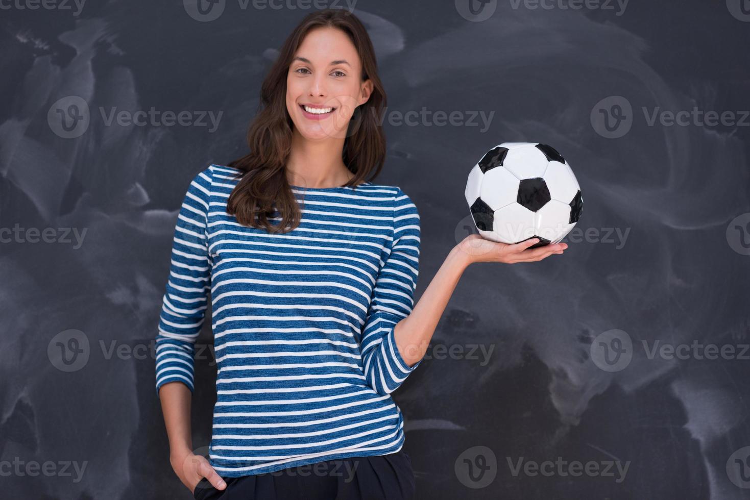 woman holding a soccer ball in front of chalk drawing board photo