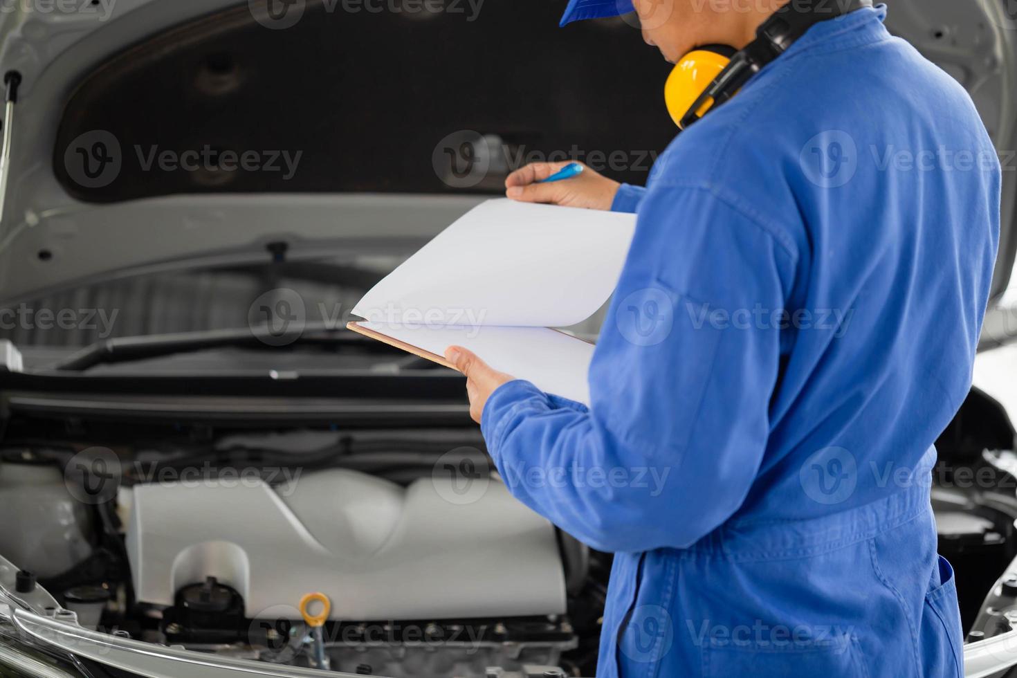 Auto mechanic holding clipboard checklist the car at mechanic shop, Mockup blank clipboard, Technician doing the checklist for repair machine a car in the garage photo