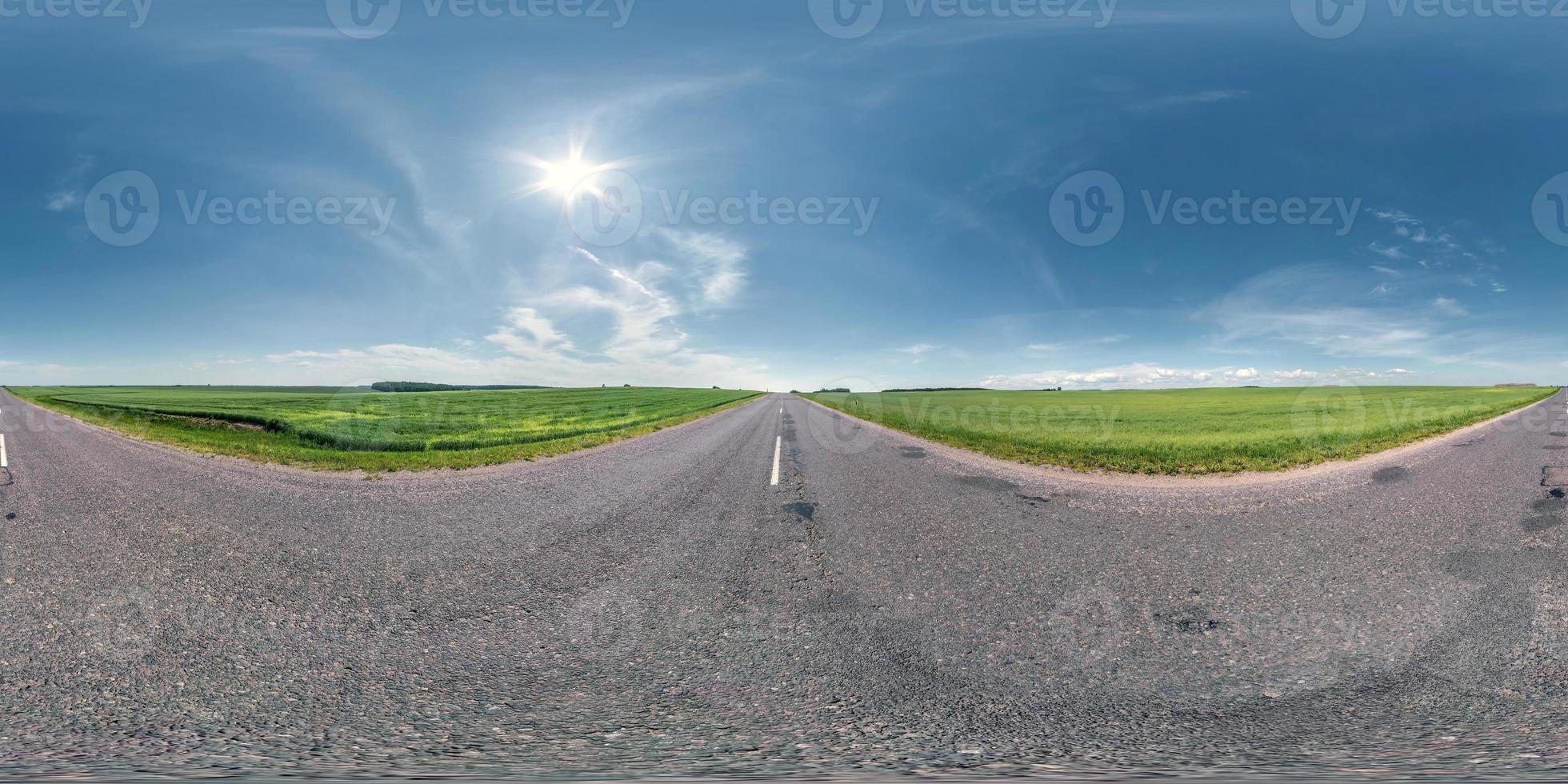 Full spherical seamless panorama 360 degrees angle view on no traffic old asphalt road among fields with clear sky in equirectangular projection, VR AR content photo