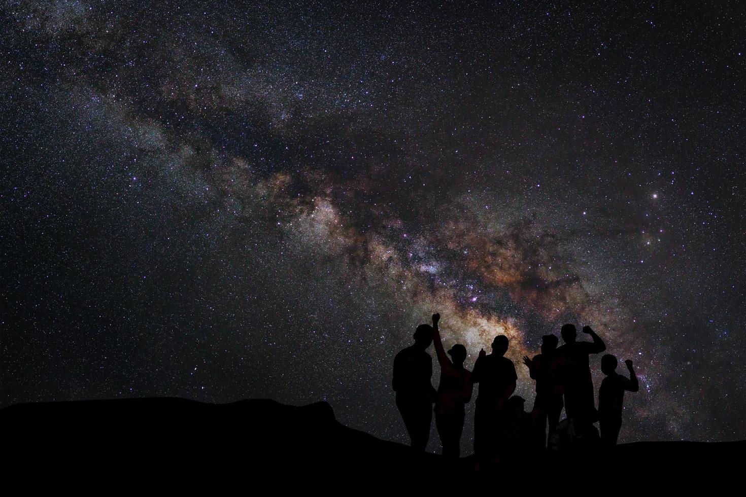 Landscape with milky way, Night sky with stars and silhouette of happy people standing on the mountain, Long exposure photograph, with grain photo