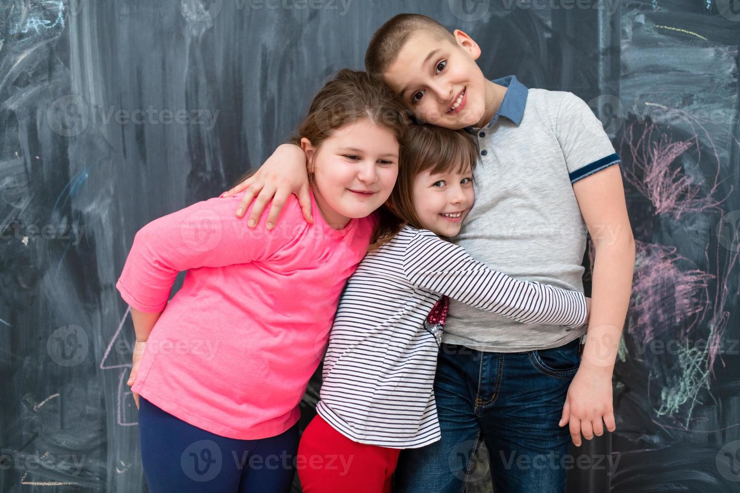 group of kids hugging in front of chalkboard photo