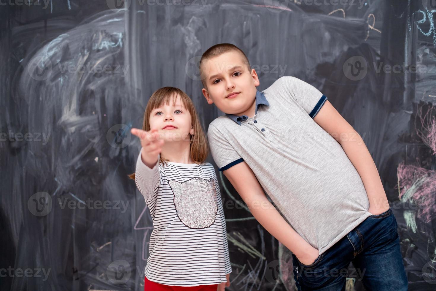 niño y niña parados frente a la pizarra foto