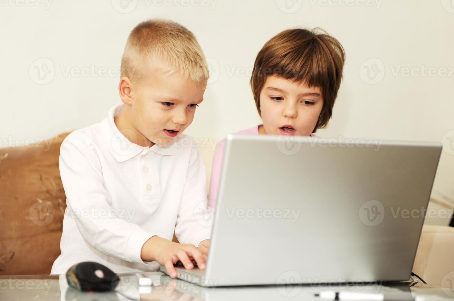 los niños se divierten y juegan en la computadora portátil foto