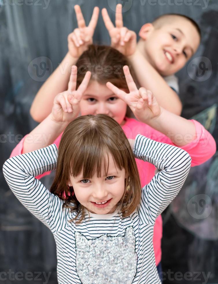 group of kids standing in front of chalkboard photo