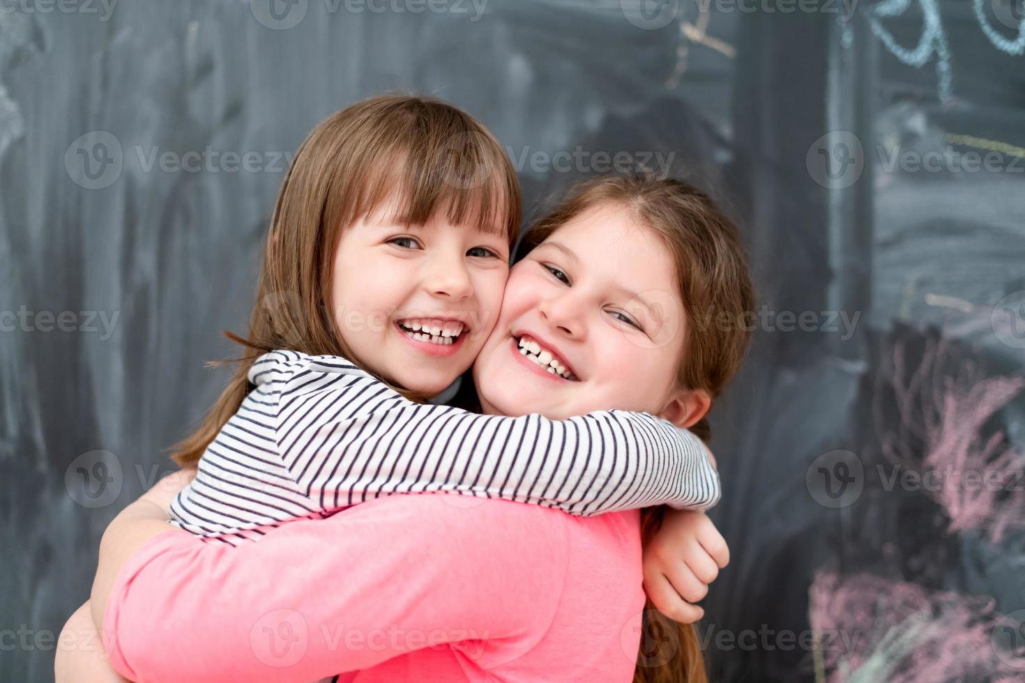 little girls hugging in front of chalkboard photo