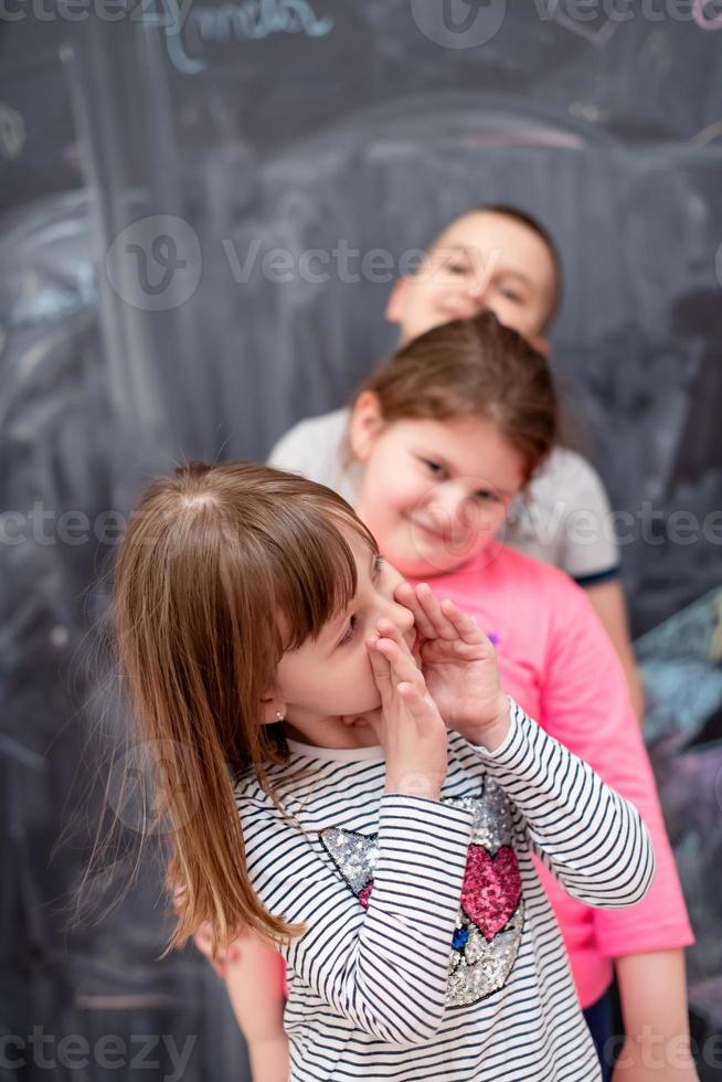 group of kids standing in front of chalkboard photo