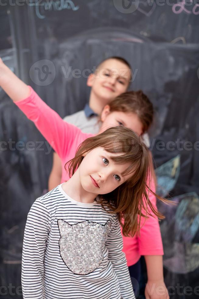 group of kids standing in front of chalkboard photo